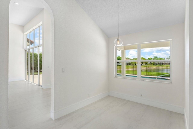 spare room with baseboards, a textured ceiling, and arched walkways
