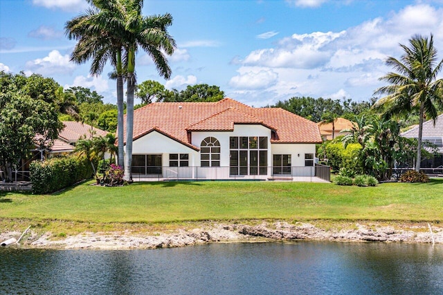 rear view of property featuring stucco siding, a sunroom, a tiled roof, and a water view