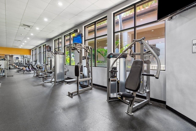 exercise room featuring healthy amount of natural light, a paneled ceiling, and baseboards
