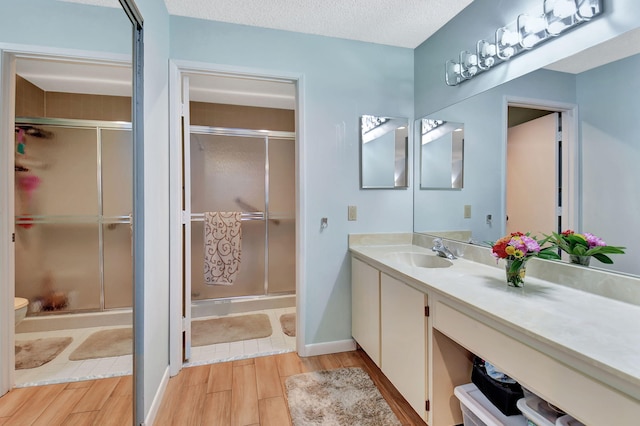 6235 Kings Gate Cir Unit C, Delray Beach, FL 33484 - bathroom featuring wood finish floors, vanity, toilet, a stall shower, and a textured ceiling
