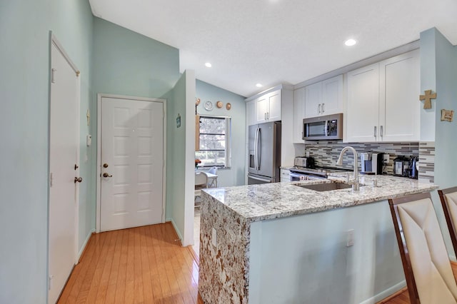 6235 Kings Gate Cir Unit C, Delray Beach, FL 33484 - kitchen featuring appliances with stainless steel finishes, a sink, light stone counters, backsplash, and white cabinets