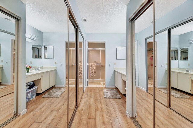 6235 Kings Gate Cir Unit C, Delray Beach, FL 33484 - bathroom with wood finished floors, two vanities, baseboards, a spacious closet, and a textured ceiling