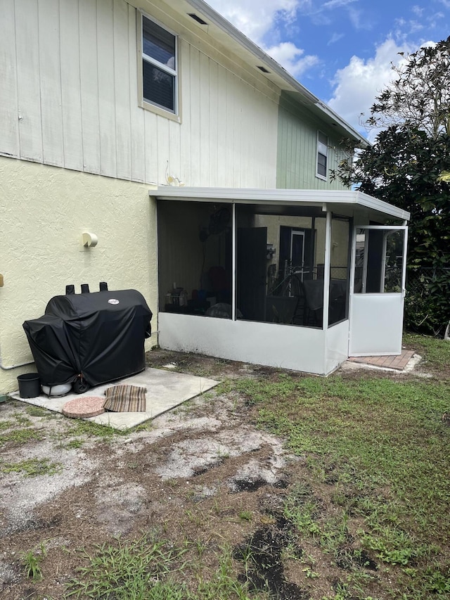 back of property with a sunroom and stucco siding