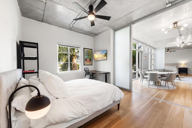 bedroom with an inviting chandelier, expansive windows, and wood finished floors