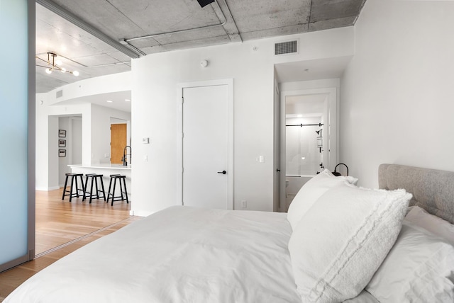 bedroom featuring an inviting chandelier, visible vents, and wood finished floors