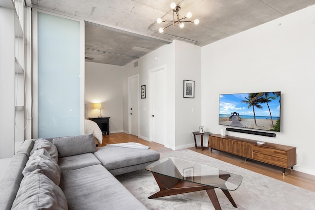living room featuring an inviting chandelier, baseboards, visible vents, and wood finished floors