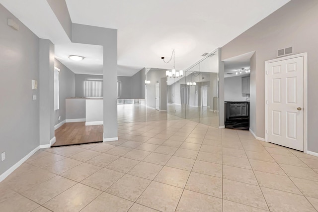 unfurnished living room featuring light tile patterned floors, a chandelier, and baseboards
