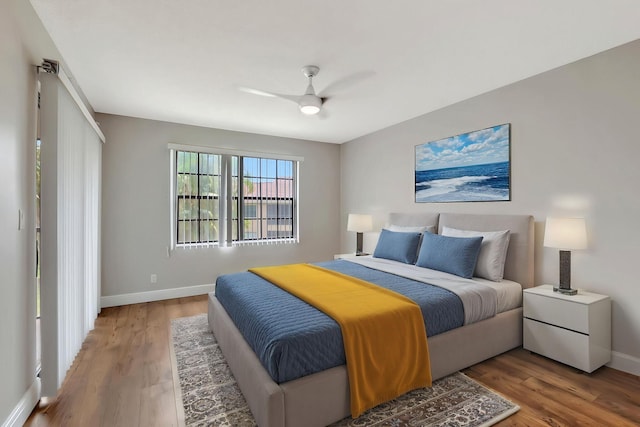 bedroom featuring baseboards, wood finished floors, and ceiling fan