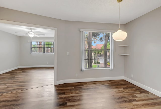 unfurnished dining area featuring plenty of natural light, wood finished floors, baseboards, and ceiling fan