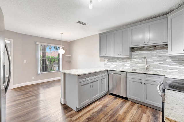 kitchen with gray cabinetry, stainless steel appliances, a peninsula, dark wood-type flooring, and a textured ceiling