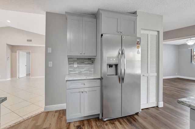 kitchen with stainless steel fridge with ice dispenser, gray cabinetry, baseboards, and tasteful backsplash