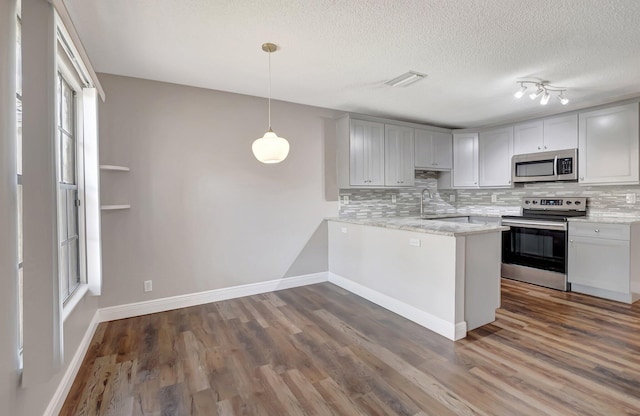 kitchen with stainless steel appliances, decorative backsplash, a peninsula, dark wood-style floors, and a textured ceiling