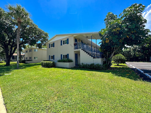 817 Lighthouse Dr Unit A, B, C, D, North Palm Beach, FL 33408 - rear view of property with stairway, stucco siding, and a lawn