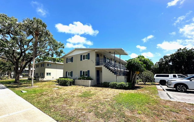 817 Lighthouse Dr Unit A, B, C, D, North Palm Beach, FL 33408 - view of side of property with stairs, stucco siding, and a lawn