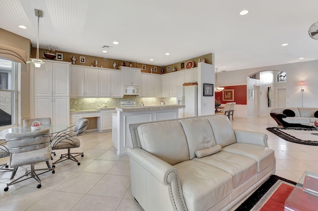 living room featuring arched walkways, light tile patterned floors, and recessed lighting