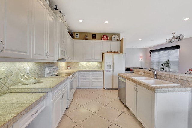 kitchen featuring white appliances, a sink, tasteful backsplash, light tile patterned floors, and white cabinetry