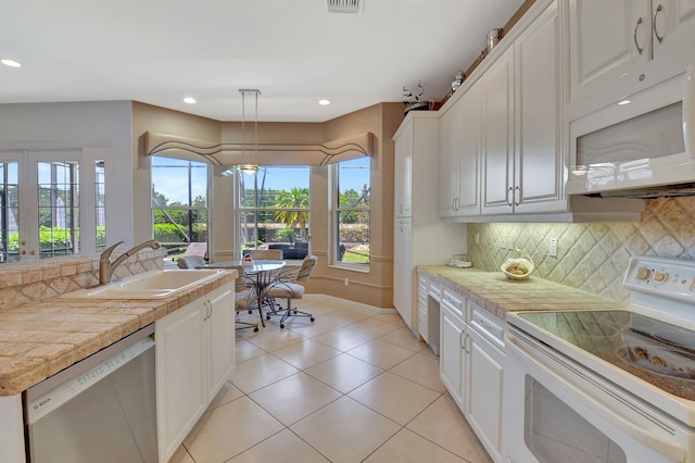 kitchen with white appliances, healthy amount of natural light, decorative backsplash, a sink, and recessed lighting