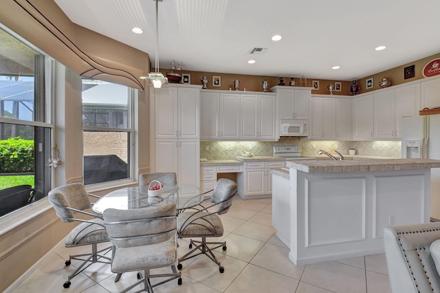 kitchen with white appliances, white cabinetry, decorative backsplash, hanging light fixtures, and recessed lighting