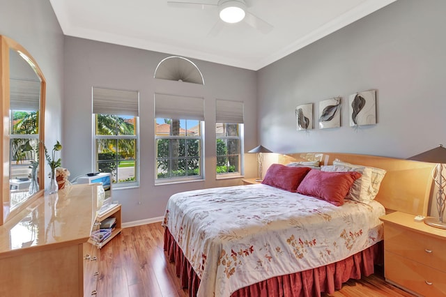 bedroom featuring light wood-style floors, baseboards, ornamental molding, and ceiling fan