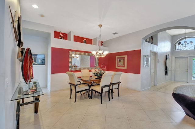 dining area with a chandelier, arched walkways, light tile patterned floors, and baseboards