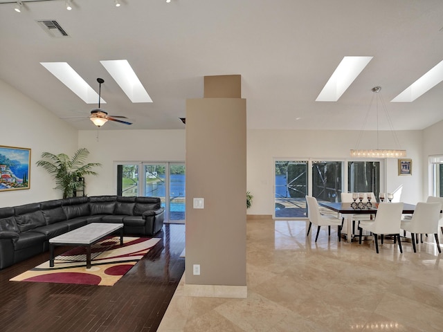 living area with a skylight, high vaulted ceiling, track lighting, and ceiling fan