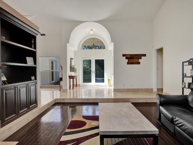 living room with french doors, wood finished floors, and a towering ceiling