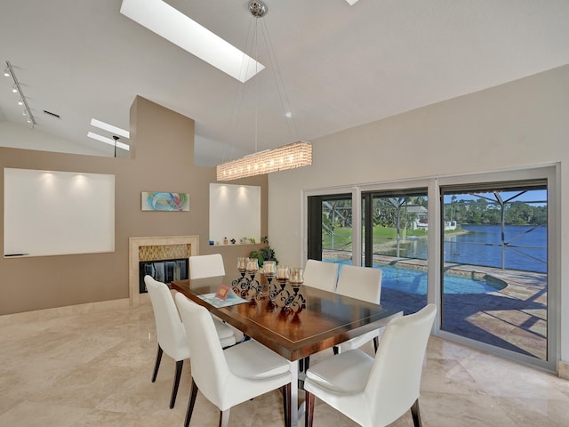 dining area with vaulted ceiling, a skylight, rail lighting, and a high end fireplace