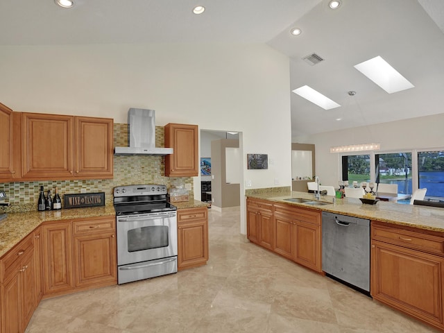 kitchen featuring stainless steel appliances, wall chimney exhaust hood, a skylight, a sink, and high vaulted ceiling