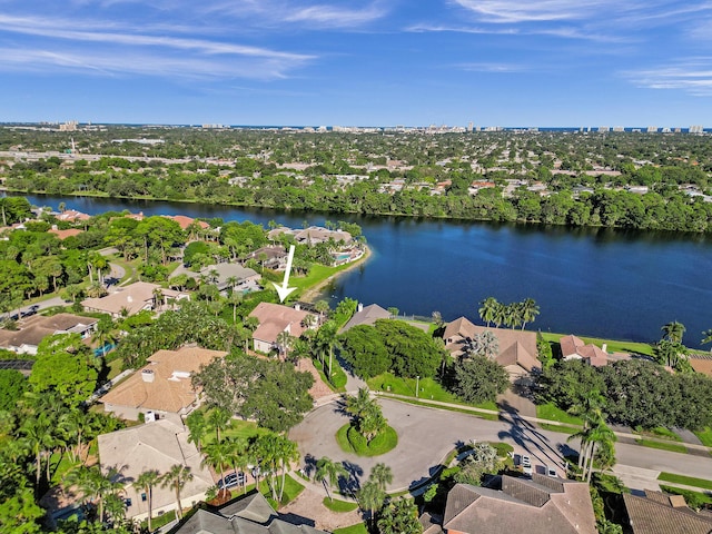 aerial overview of property's location featuring a large body of water, nearby suburban area, and a tree filled landscape