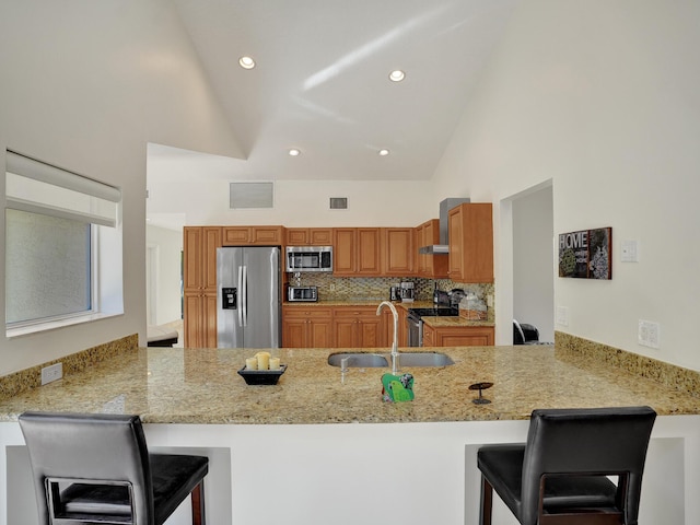 kitchen with stainless steel appliances, a sink, a peninsula, high vaulted ceiling, and light stone countertops