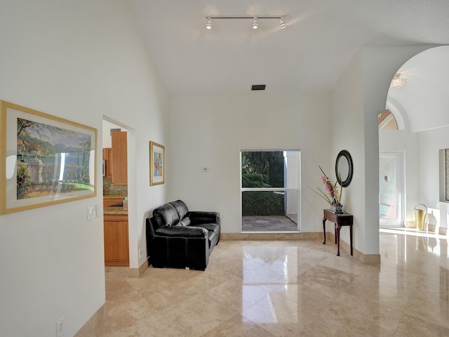 sitting room with high vaulted ceiling and light marble finish flooring