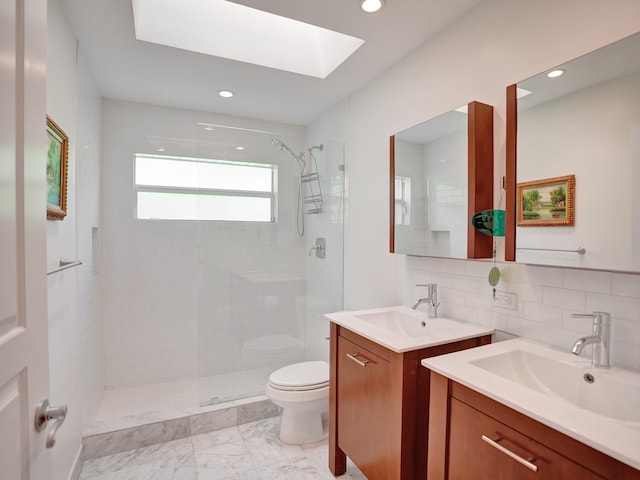 full bath with a skylight, tiled shower, toilet, decorative backsplash, and two vanities