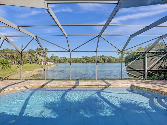 outdoor pool featuring glass enclosure, a water view, and a patio
