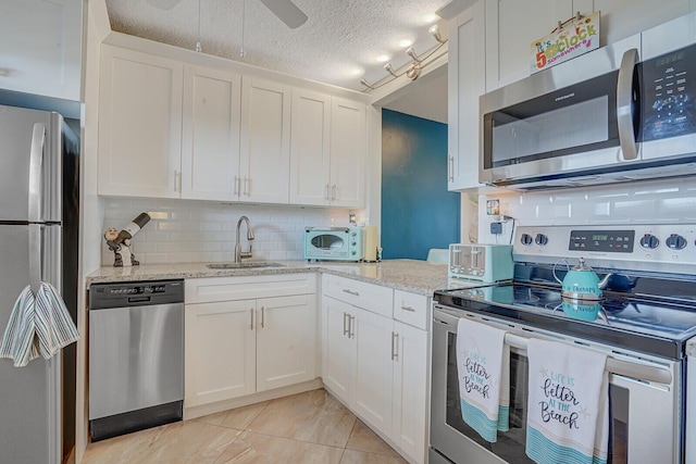 2724 N Garden Dr Unit 302, Lake Worth, FL 33461 - kitchen with stainless steel appliances, a sink, backsplash, white cabinets, and a textured ceiling
