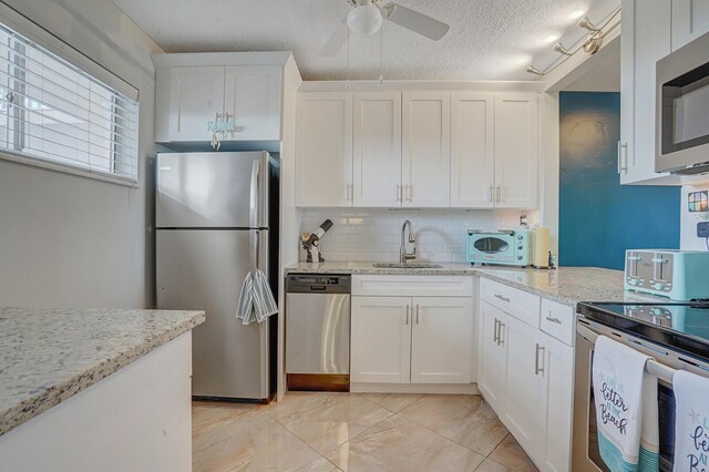 2724 N Garden Dr Unit 302, Lake Worth, FL 33461 - kitchen with stainless steel appliances, a sink, backsplash, white cabinets, and a textured ceiling