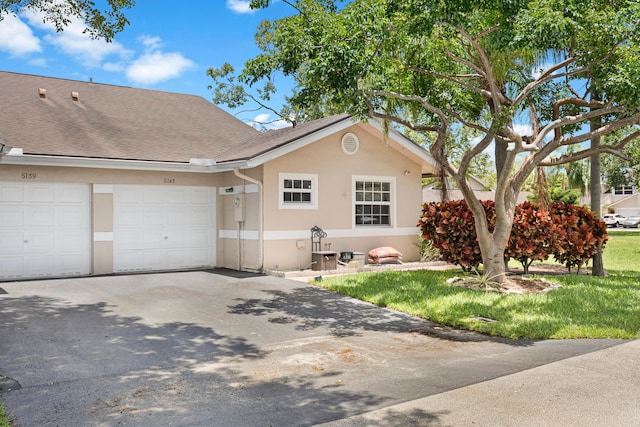 ranch-style house featuring a garage, stucco siding, asphalt driveway, and a shingled roof