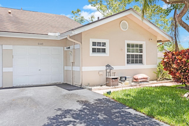 single story home featuring stucco siding, an attached garage, and driveway