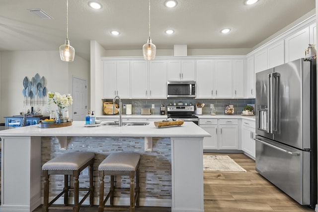 kitchen featuring stainless steel appliances, a sink, light countertops, white cabinets, and light wood-style flooring