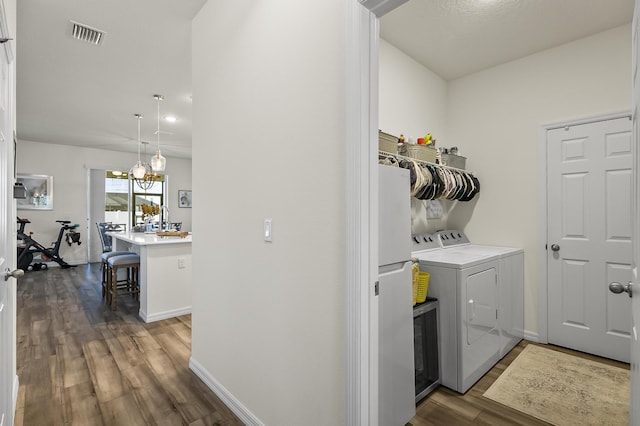 laundry room featuring dark wood-style flooring, washing machine and clothes dryer, and baseboards