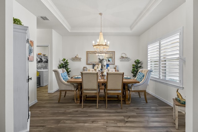 dining room with a chandelier, wood finished floors, a raised ceiling, ornamental molding, and independent washer and dryer