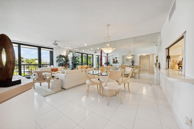 dining space with plenty of natural light, light tile patterned floors, ceiling fan, expansive windows, and a textured ceiling