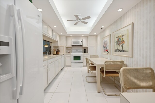kitchen featuring white appliances, wallpapered walls, light countertops, a ceiling fan, and a sink
