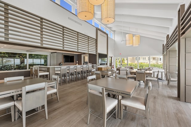 dining space with a high ceiling, healthy amount of natural light, and wood finished floors