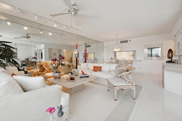 living room featuring a ceiling fan, a textured ceiling, and light tile patterned flooring
