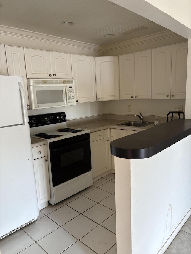 kitchen with white appliances, a sink, a peninsula, white cabinets, and crown molding