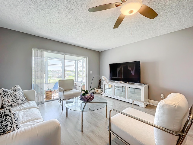 living room with a textured ceiling, wood finished floors, and a ceiling fan