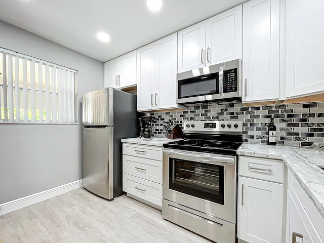 kitchen with stainless steel appliances, decorative backsplash, white cabinets, light stone counters, and recessed lighting