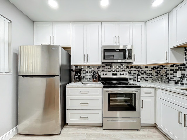 kitchen with appliances with stainless steel finishes, white cabinetry, decorative backsplash, light stone counters, and recessed lighting