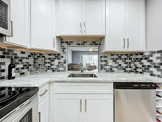 kitchen with appliances with stainless steel finishes, white cabinets, tasteful backsplash, and a sink