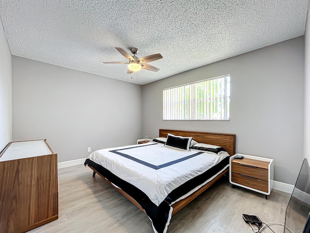 bedroom featuring light wood-style floors, baseboards, a textured ceiling, and ceiling fan